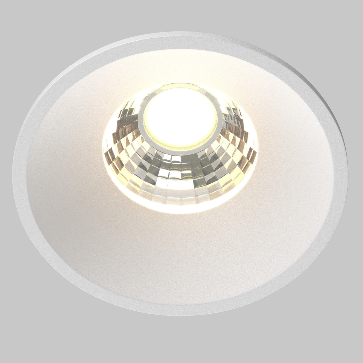 A close-up of the Round LED Recessed Downlight 7W 3000K in white shows its durable aluminum construction and reflective, faceted interior surface, emitting a warm 3000K light that creates patterns on a plain, light-colored ceiling.