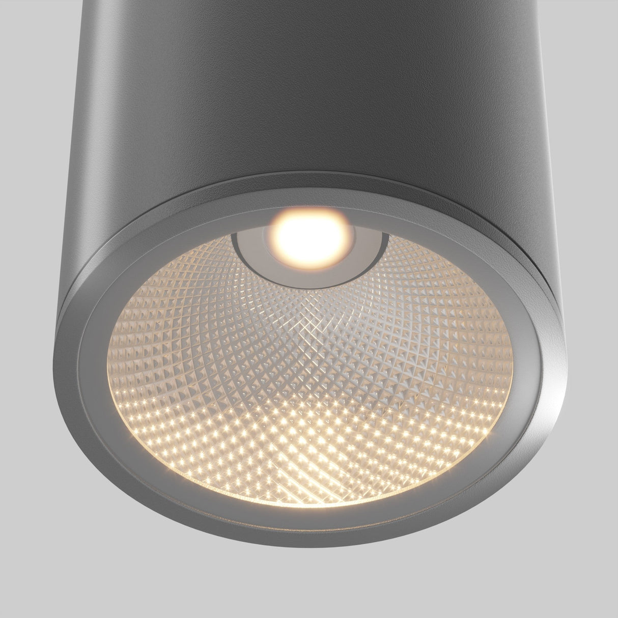 Close-up of the Bar Outdoor LED Downlight (12W, 3000K) with a textured metallic interior, emitting a warm glow. Its sleek gray exterior in a graphite finish offers a modern, minimalist design, making it perfect as energy-efficient lighting for any space.