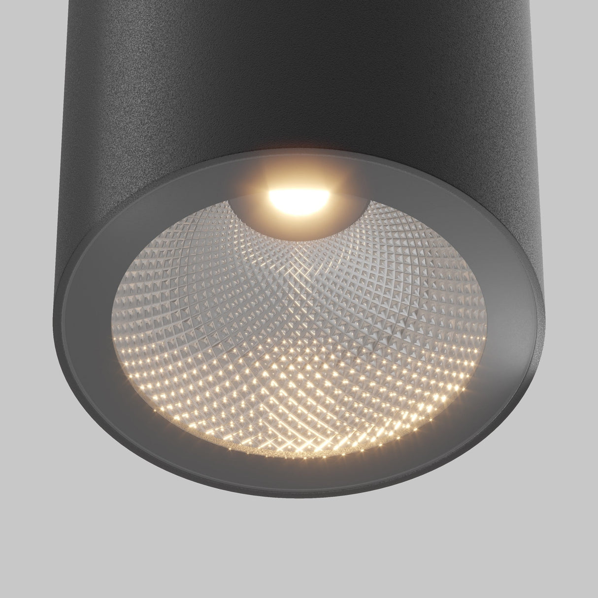Close-up of the Roll Outdoor Downlight - Black, a modern cylindrical light made from durable aluminum with a textured interior, casting a soft warm glow against a neutral background.