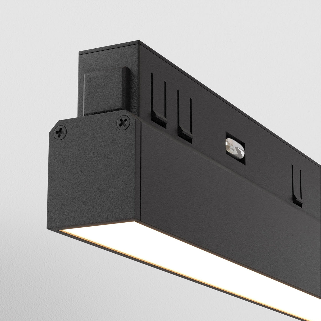 A close-up of the Basis LED Linear Track Light for Magnetic Exility 12W 3000K in black reveals its modern rectangular design with a bright LED strip. Its sleek, minimalist style with visible screws and geometric lines stands out against a plain white background.