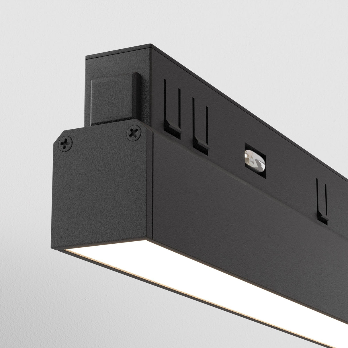 Close-up of a modern black Basis LED Linear Track Light for Magnetic Exility 12W 4000K. Its minimalist design emits light from the bottom, accentuating textures on a white ceiling, ideal for contemporary interiors.