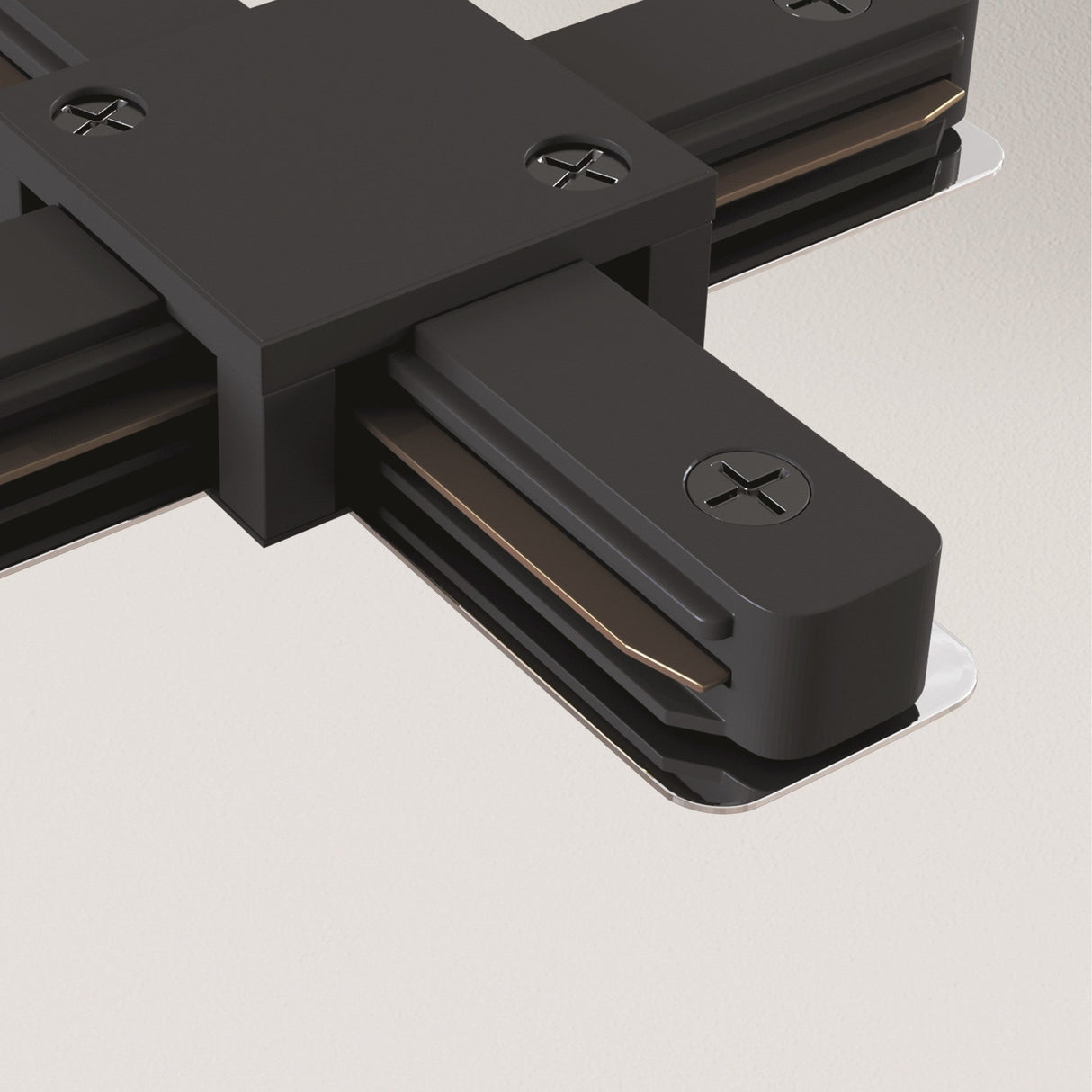 Close-up of the Unity Single Phase Surface-Mounted Track X-Connector in black, showing screws and metal tracks on a light surface. This cross-shaped connector allows for multi-directional lighting connections.