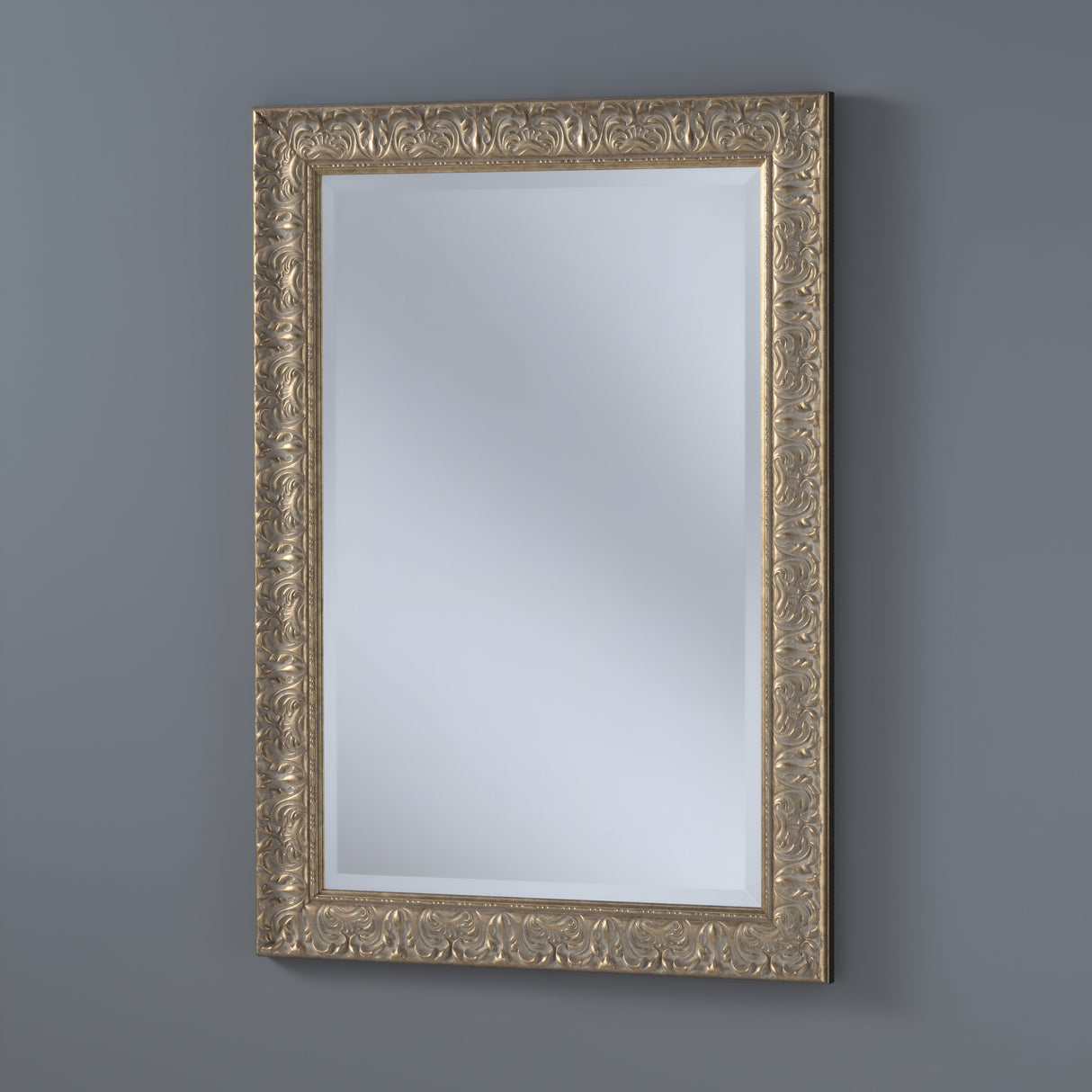 The Elyssar Rectangle Wall Mirror, with its ornate gold frame and intricate floral design, enhances a gray wall with vintage-inspired decor.
