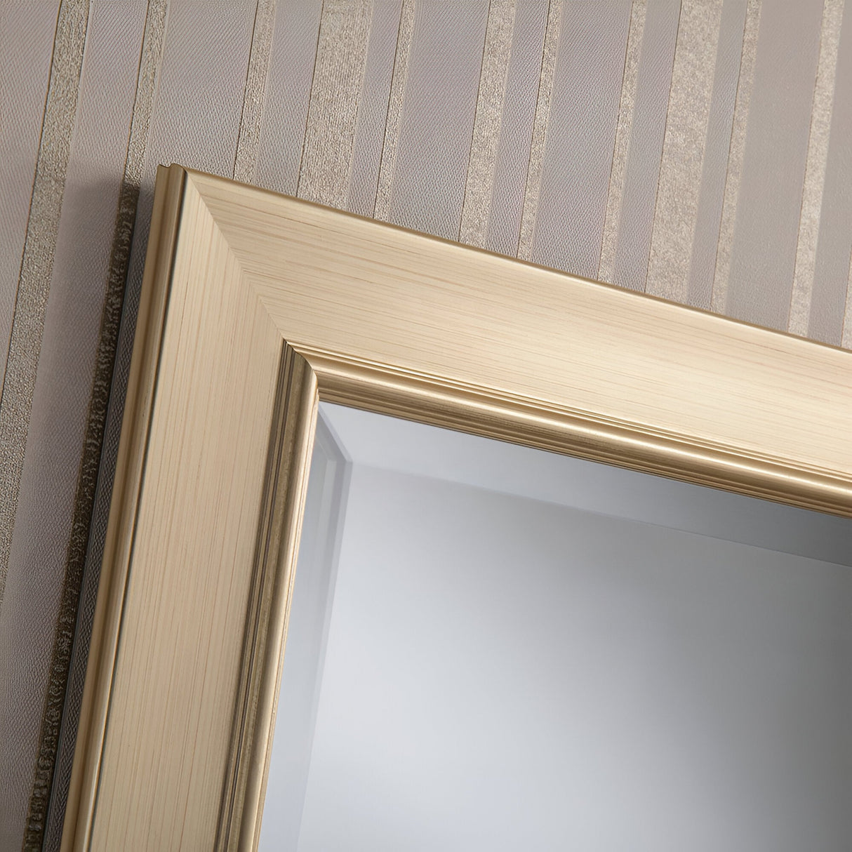 Close-up of a Rimini Rectangle Wall Mirror - Gold hung on a wall with textured vertical stripes in muted tones.
