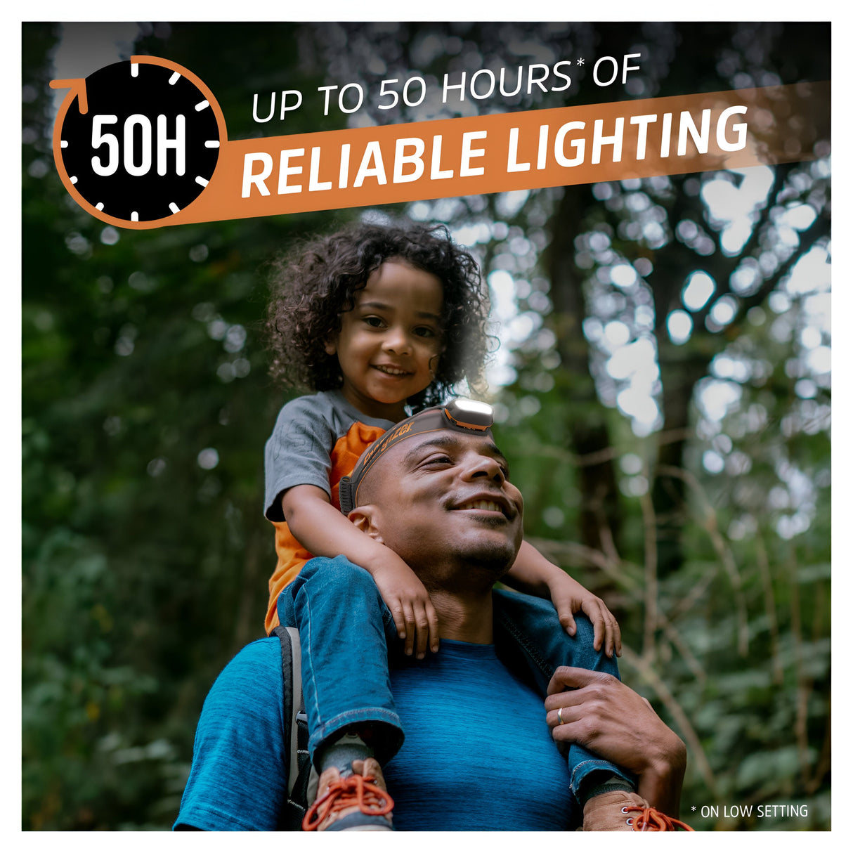 In a forest setting, a man with a cheerful child perched on his shoulders strolls, utilizing the Energizer Rechargeable LED Head Torch 750 Lumens - Batteries Included, which features a pivoting head. Text overlay displays "Up to 50 hours of reliable lighting (on low setting)" accompanied by a clock icon indicating 50H.