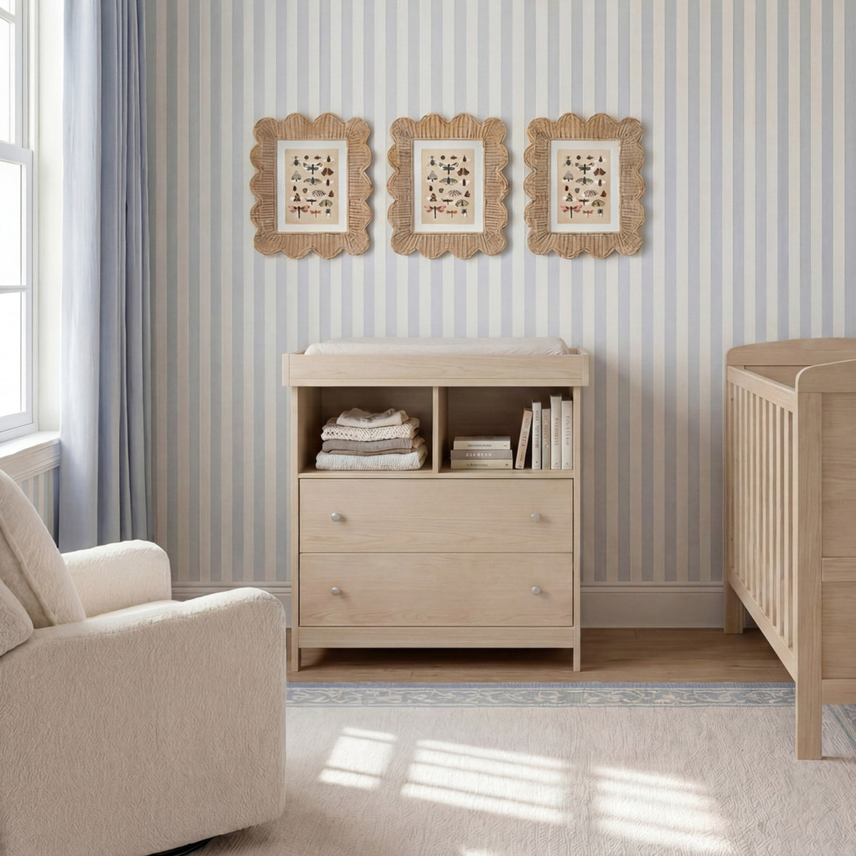 Seeker Changing Table with Drawers in Nordic natural wood finish, shown in a nursery with open shelving, two drawers with round knobs, and a removable changing top.