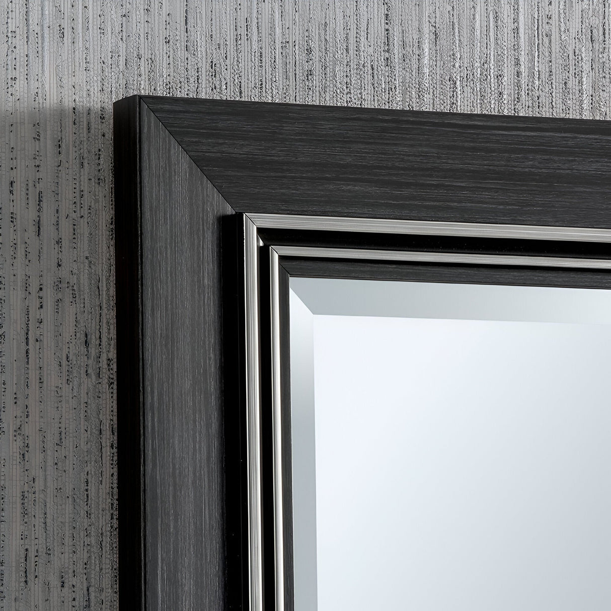 Close-up of the Alaris Rectangle Wall Mirror - Black, showcasing its sleek black wooden frame with a metallic inner edge. It is set against a textured gray wall that perfectly complements the mirror's modern design, making it ideal for contemporary interiors.