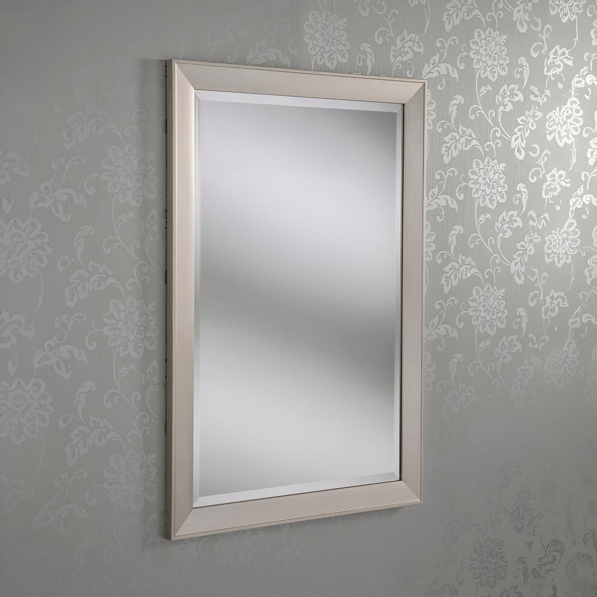 The Sicily Rectangle Wall Mirror - Silver, with its light-colored frame, adorns a wall covered in patterned floral wallpaper. It reflects light brilliantly, effortlessly enhancing modern home decor.