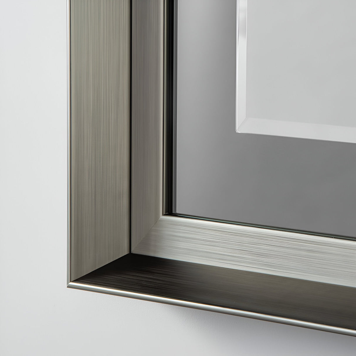 Close-up of a sleek, modern corner of the Sloane Rectangle Wall Mirror with a grey lacquered finish and reflective surface. The mirror's smooth texture enhances its minimalist and stylish design, exuding modern sophistication. Its neutral background beautifully highlights the intricate details.