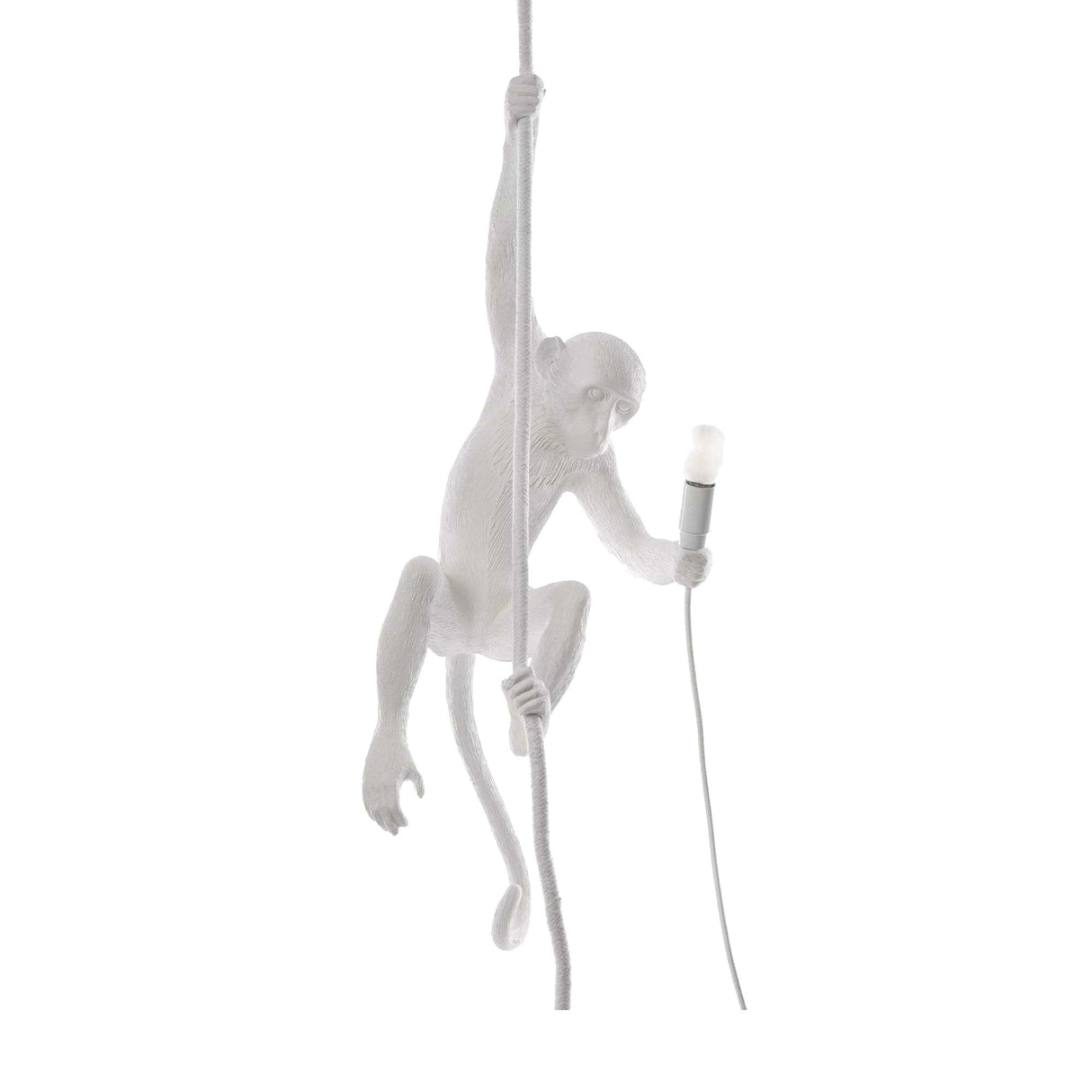 The Monkey 1 Light Pendant - White features a sculptural white monkey hanging from a rope with one hand and holding a lit lightbulb in the other, creating a striking accent against any plain backdrop.