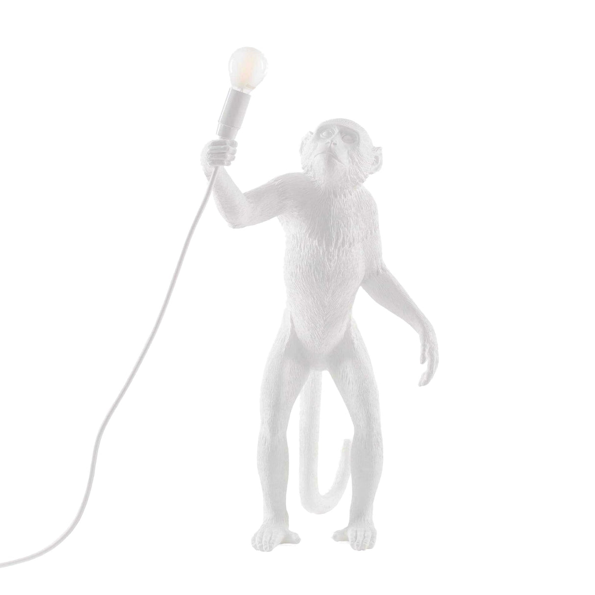 The Monkey Standing Table Lamp - White features a statue holding a lit bulb upright against a plain white background—a whimsical decor piece and unique lighting accent for any room.