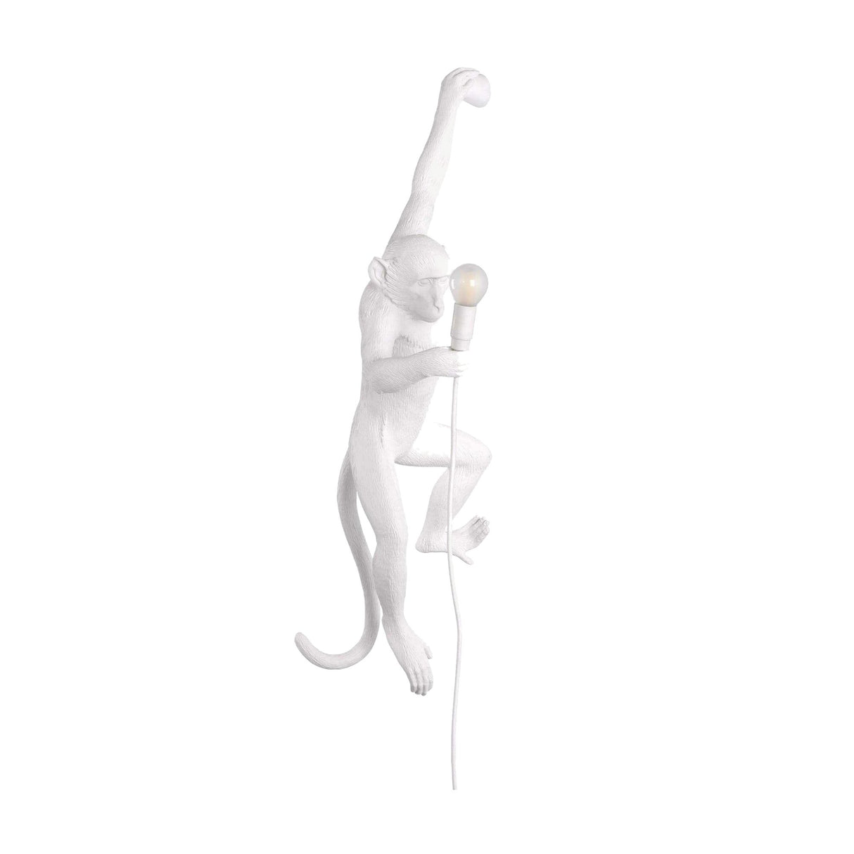 The Monkey Wall Lamp - White features a hanging monkey sculpture holding a light bulb, with an artistic design and visible cord that bring creativity to any plain white wall.