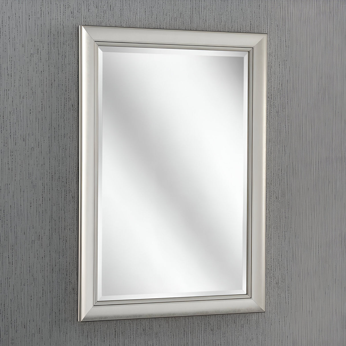 The Tivoli Rectangle Wall Mirror - Silver boasts a sleek silver frame mounted on a textured gray wall, enhancing the space by reflecting light and adding a bright, modern touch to the decor.