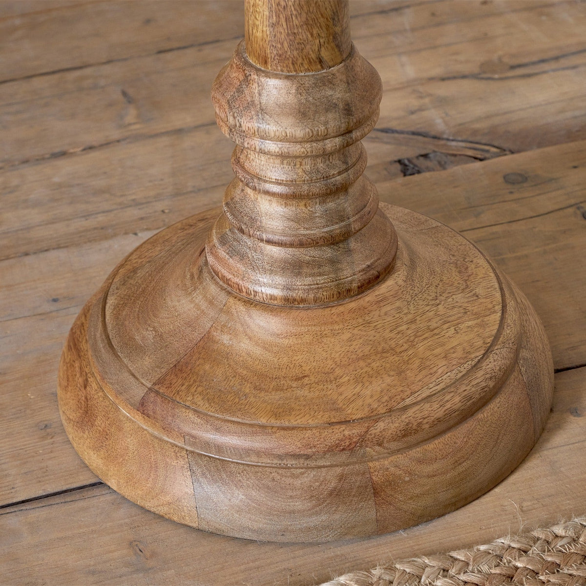 Close-up of the Usha Classic Wooden Floor Lamp Base in natural mango wood, showing the domed foot and turned rings on the tapering column, set on a wooden floor.