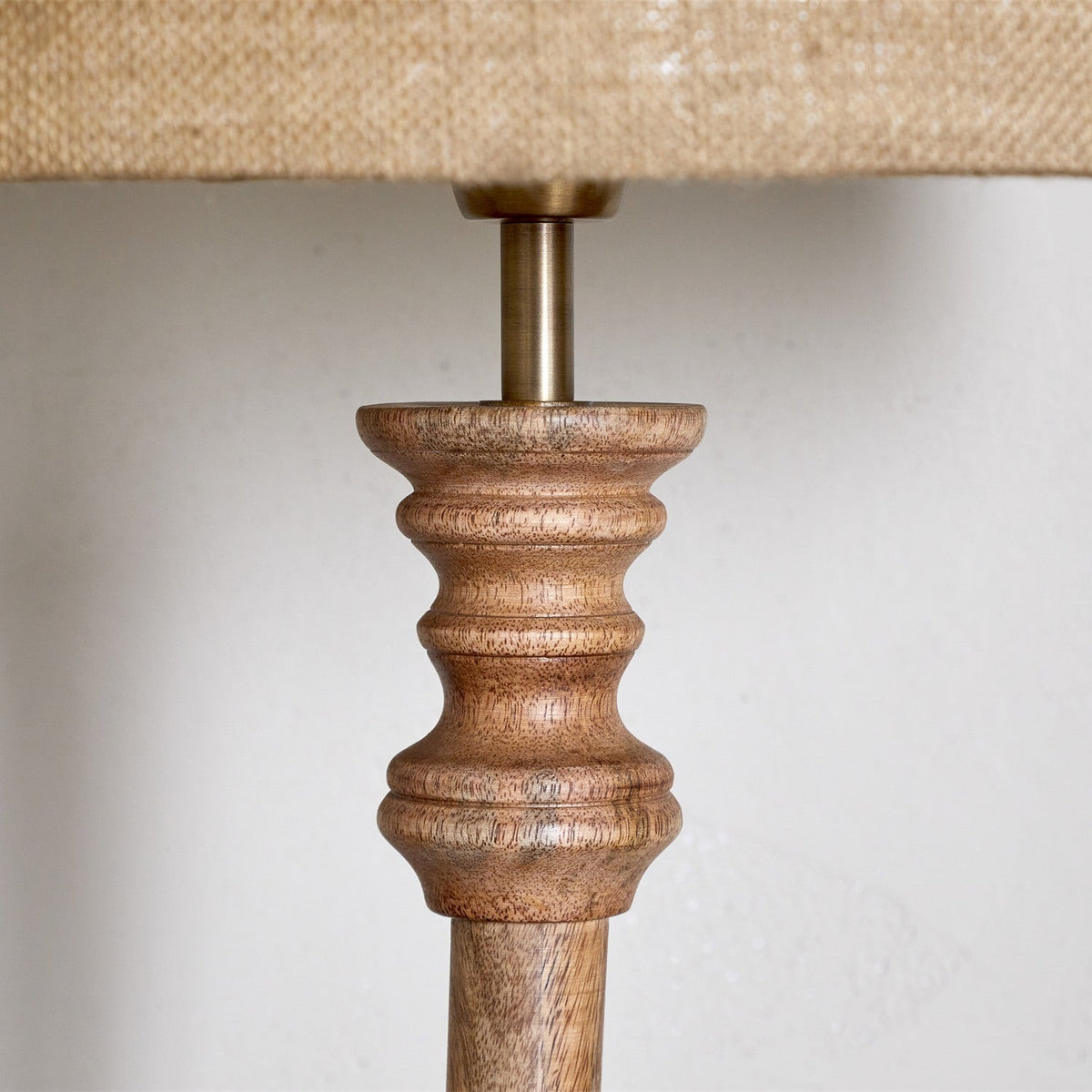 Close-up of the Usha Classic Wooden Floor Lamp Base in natural mango wood, showing turned rings and brass lampholder fitting against a plain background.
