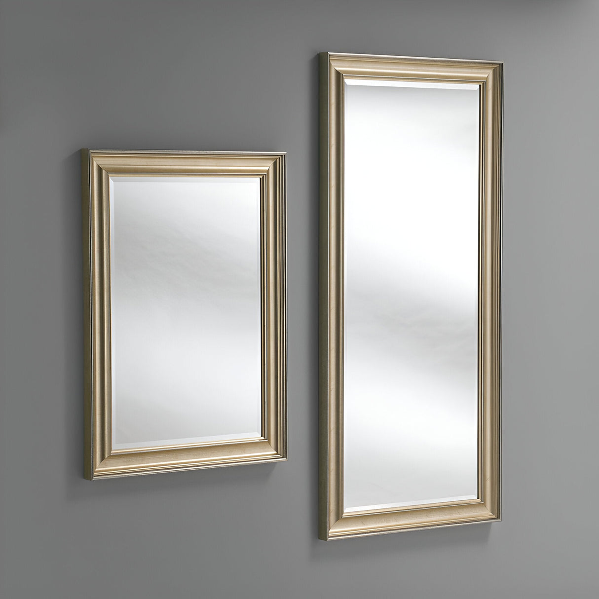 A pair of rectangular mirrors adorn the gray wall, infusing elegance into your home decor. The smaller mirror on the left is positioned slightly higher than the Luxon Rectangle Wall Mirror in champagne on the right.