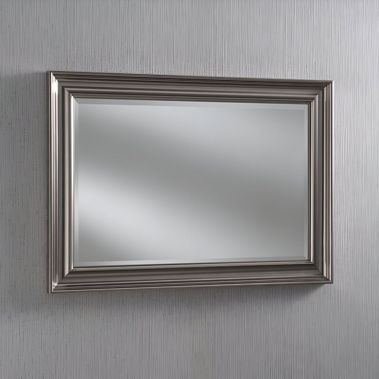 The Luxon Rectangle Wall Mirror - Grey is mounted on a textured, light-colored wall, enhancing the minimalist home decor of the room with its sleek design and reflective surface.