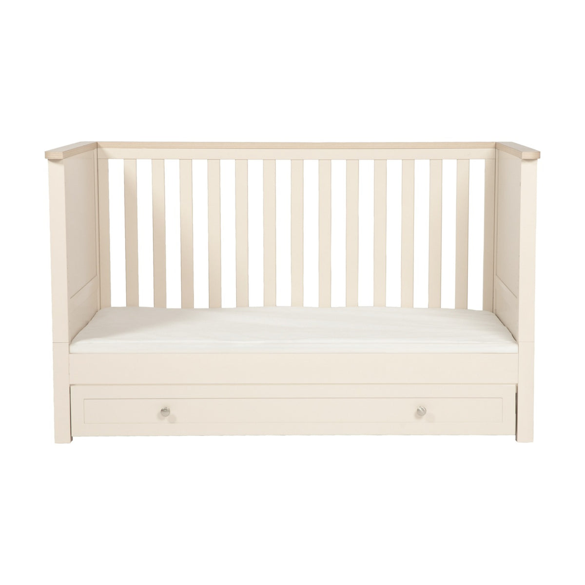 Wanderer Convertible Cot Bed with Drawer in Cashmere, featuring slatted sides, oak-effect trim, mattress base, and an under-bed storage drawer with round knobs, shown on a plain white background.