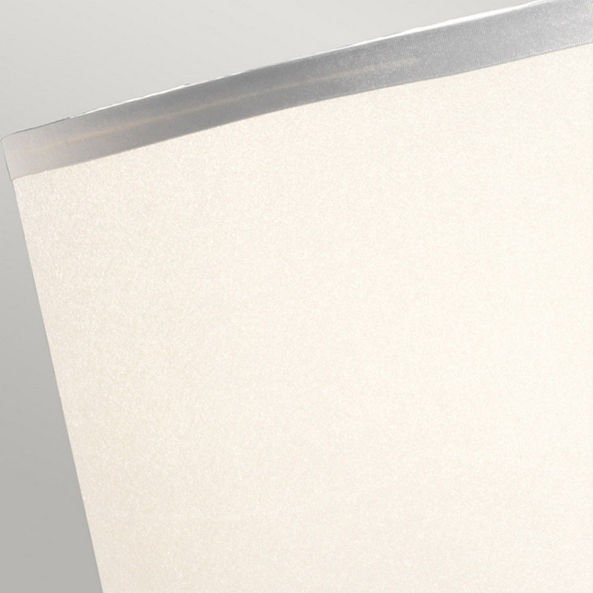 A close-up of a sheet of parchment paper with a slightly curved edge against a neutral background, subtly capturing light reminiscent of the soft glow from an Aegeus 1 Light Table Lamp - Polished Nickel. The paper's smooth texture and translucence add an elegant touch to its simple beauty.