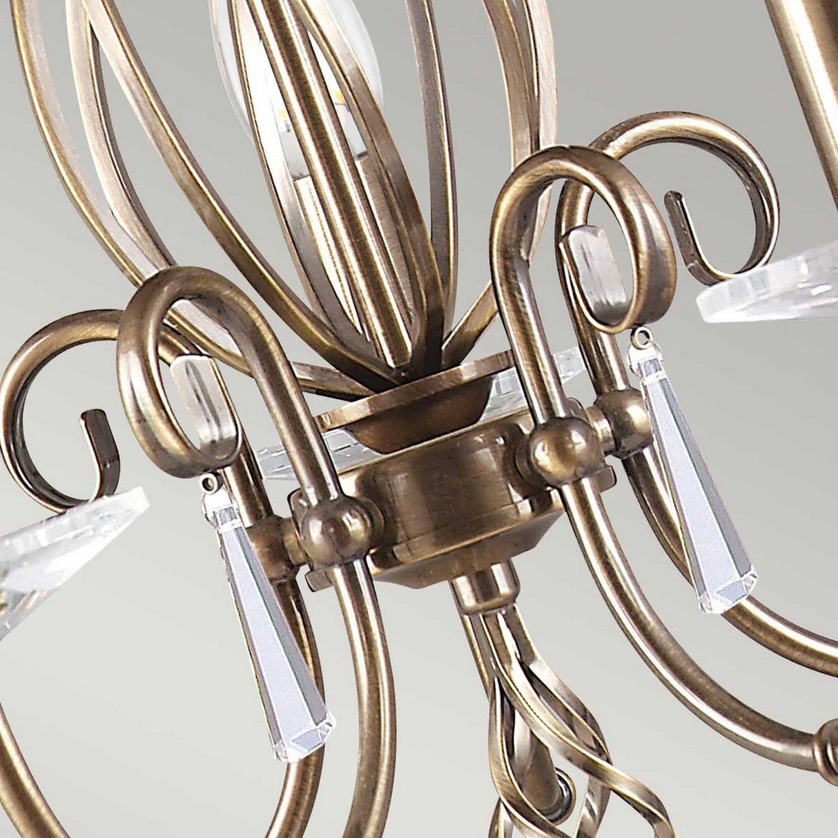 Close-up of the Aegean 5 Light Chandelier - Aged Brass, showcasing its ornate design with swirling arms and clear crystal pendants hanging from each meticulously crafted scroll. The chandelier exudes an elegant and vintage appeal.