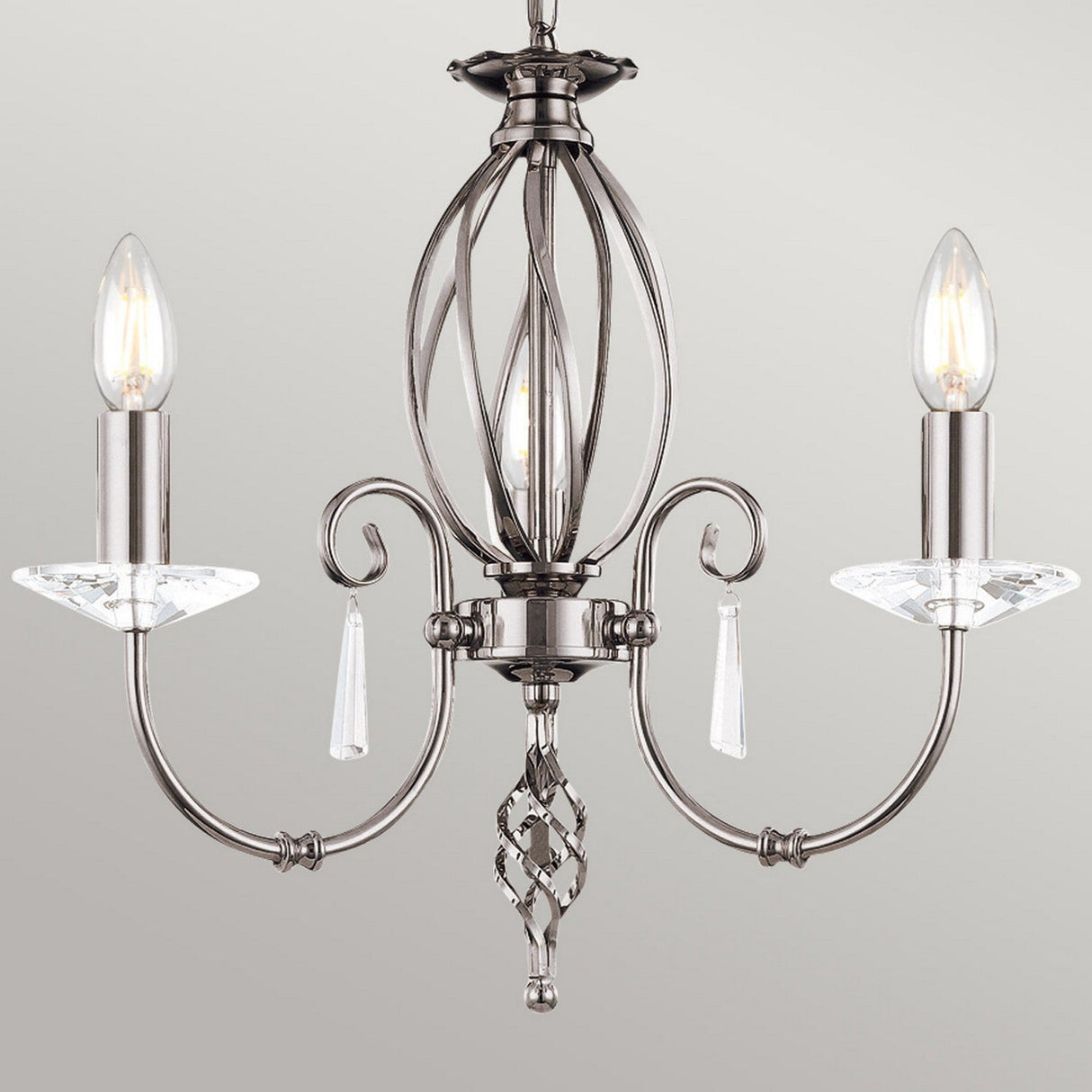 The Aegean 5 Light Chandelier in polished nickel showcases hand-forged scrolls and crystal accents, complete with two candle-shaped light bulbs set against a gray backdrop.