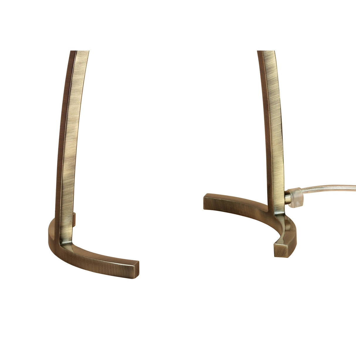 Close-up of the curved, antique brass-finished metal legs of the Alaska 1 Light Table Lamp, displayed on a white background with a visible clear electrical cord on the right side.