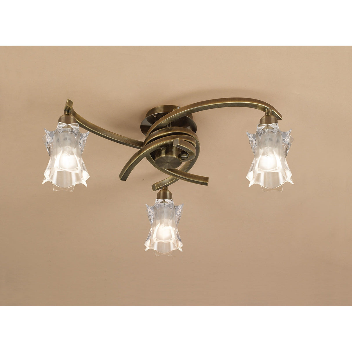 Mantra Alaska 3 Light semi-flush ceiling light in antique brass with curved swirling arms and sculpted frosted star-shaped glass shades.