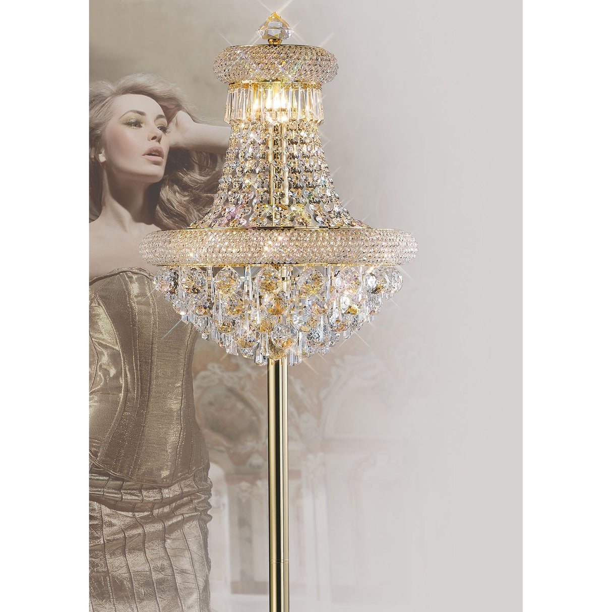The Alexandra 6 Light Crystal Floor Lamp in polished chrome stands in the foreground, its ambient glow illuminating the scene as a woman in a gold corset gown poses elegantly in the gently blurred background.