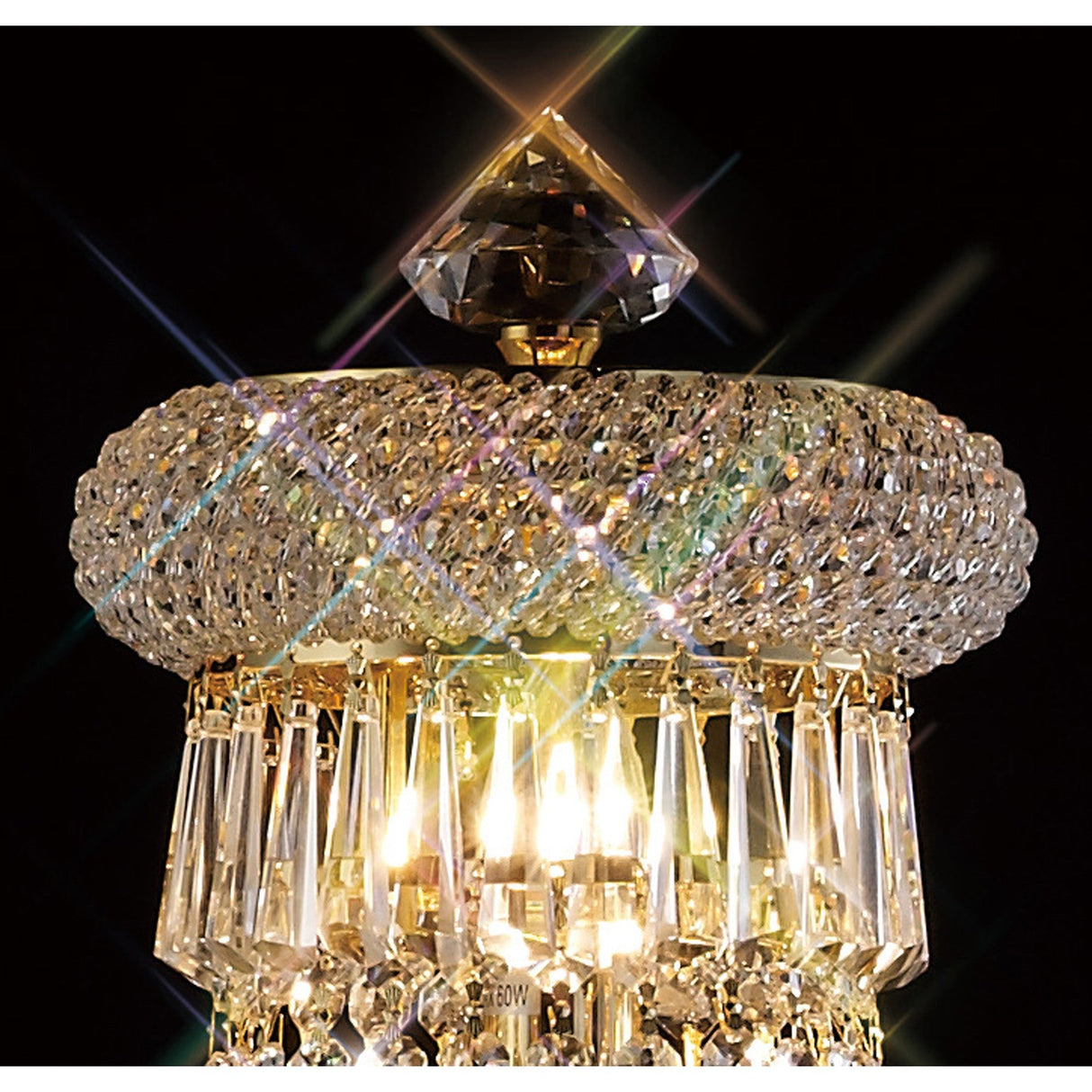 A close-up of the Alexandra 6 Light Crystal Floor Lamp in gold, showcasing intricate glass detailing and hanging prisms that reflect bright light and cast rainbow sparkles against a dark background.