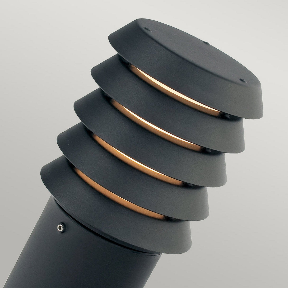 Close-up of the Alta 1 Light Medium Bollard in matte black, featuring a modern design with horizontal ridges that reveal light. The background is a neutral gray.
