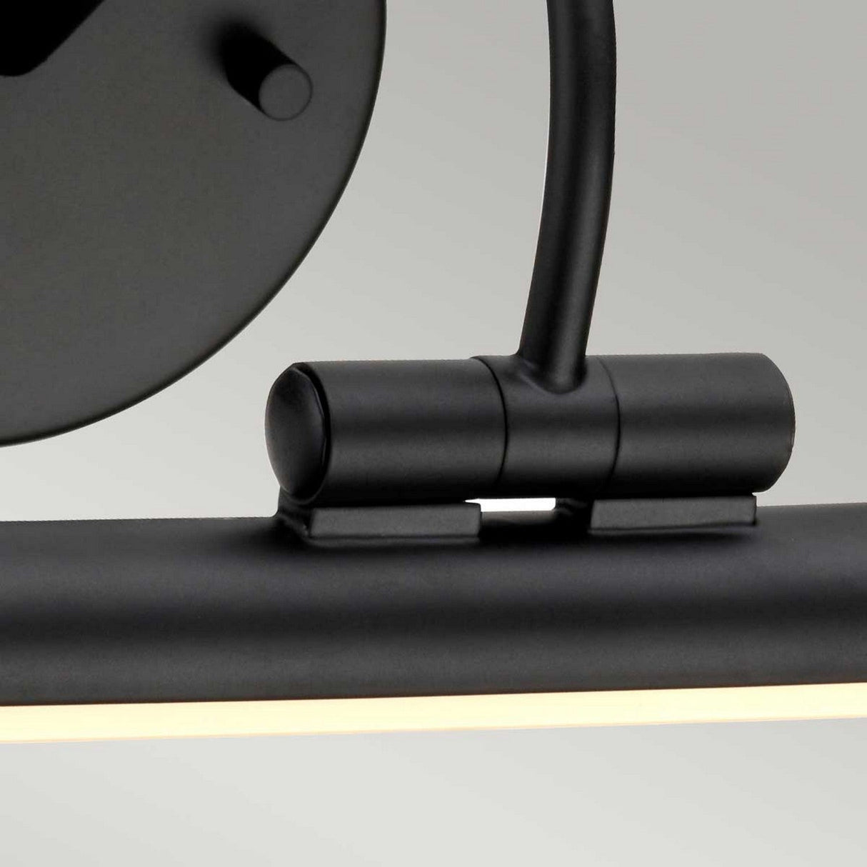 Close-up view of the Alton 1 Light Large LED Picture Light in black, featuring an adjustable cylindrical design with a curved arm attached to a circular base. The black finish complements its sleek appearance as it emits a soft glow.
