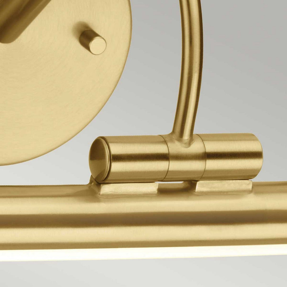 Close-up of the Alton 1 Light Small LED Picture Light in brushed brass, showcasing its gold-colored hinge mechanism. The design is sleek and modern, with a smooth and streamlined appearance against a neutral gray background.