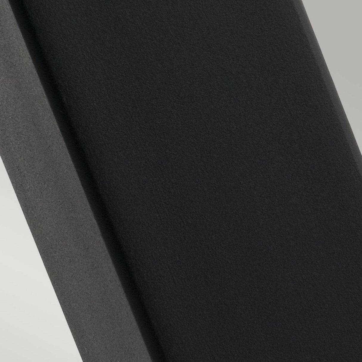 The Arendal 1 Light Large Bollard in Black features a textured dark gray or black metallic surface, likely part of its rectangular design, with soft lighting that highlights its smoothness and gentle shadows. This durable lighting solution is perfect for outdoor landscape lighting in coastal environments.