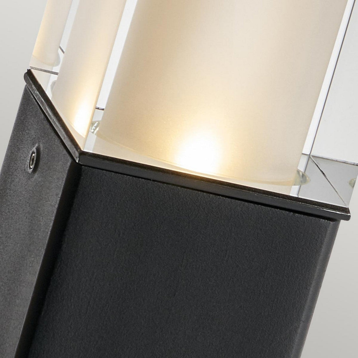 Close-up of the Arendal 1 Light Large Bollard in black, featuring a cylindrical frosted glass cover and a sleek base. This durable lighting solution emits a soft, warm glow, making it ideal for coastal environments.