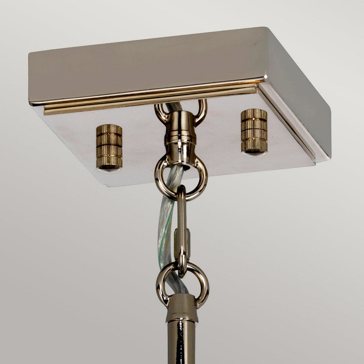 Close-up of the Aries 4 Light Large Chandelier featuring a polished nickel square mount. It has two decorative knobs and a transparent power cord attached to its chain, hanging down against a soft gray background.