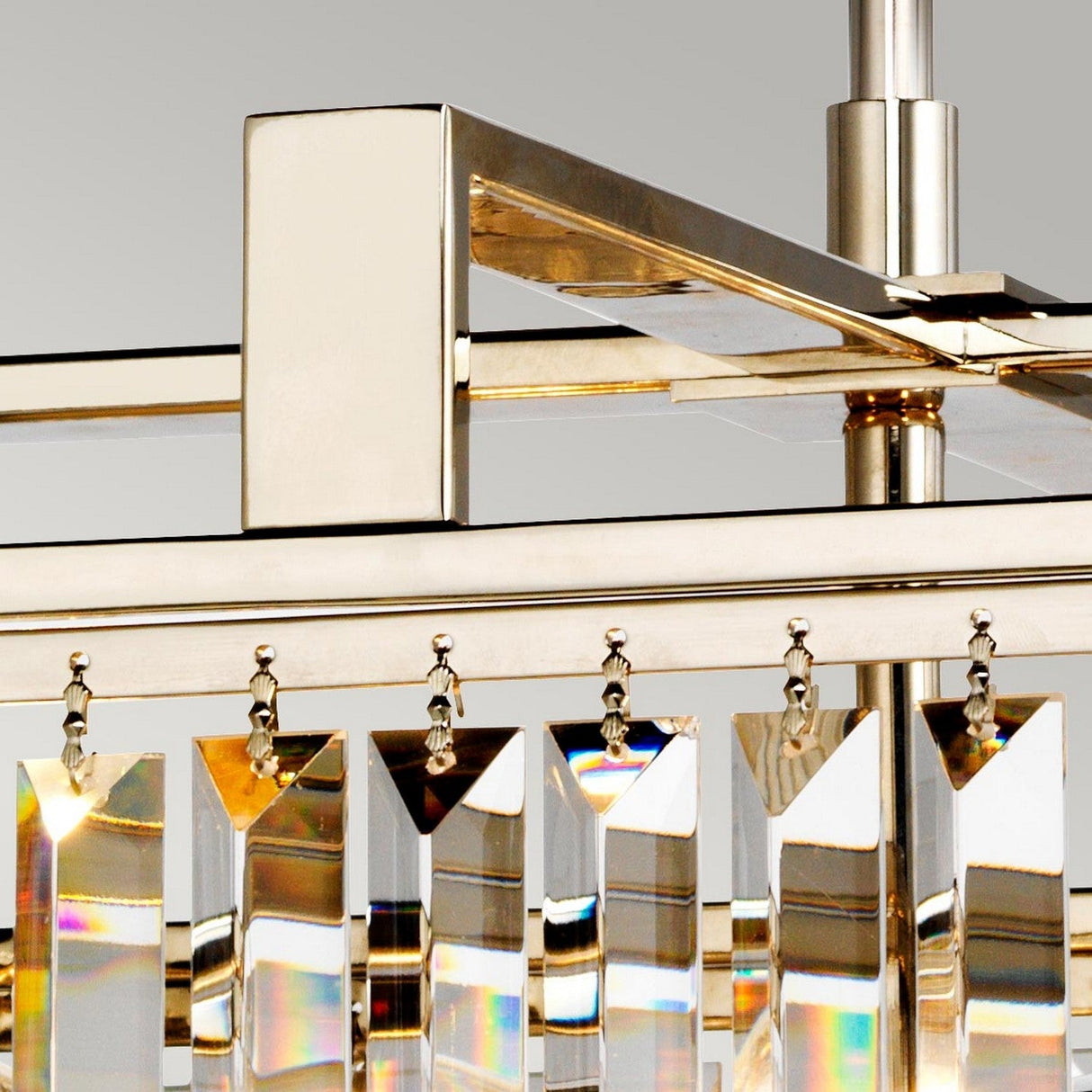 A close-up of the Aries 4 Light Large Chandelier - Polished Nickel highlights its rectangular cut glass crystals reflecting light and creating a rainbow effect. The chandelier's modern, geometric design showcases straight lines and polished nickel accents.