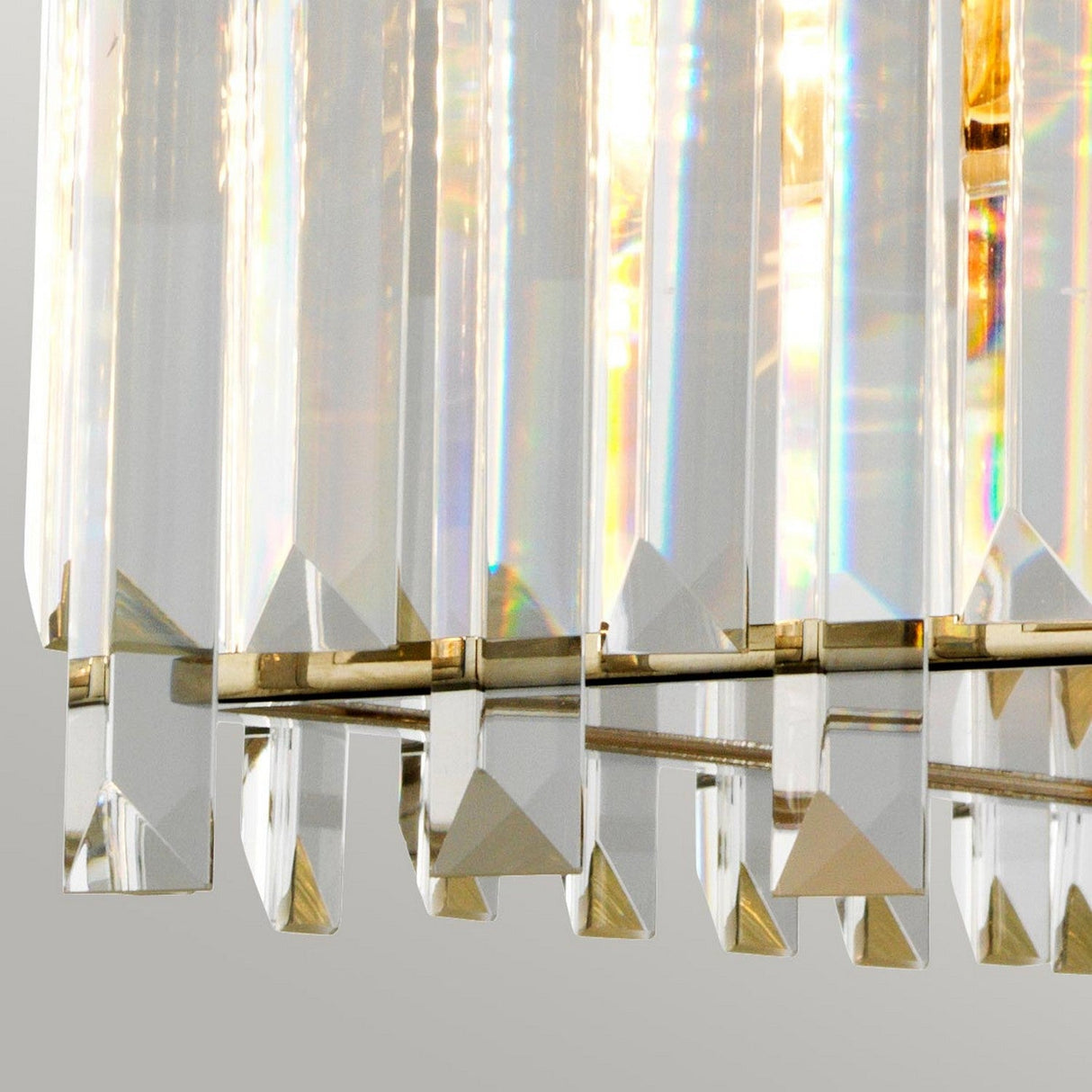 A close-up of the Aries 4 Light Large Chandelier - Polished Nickel, featuring vertical cut glass crystals that refract light into a vibrant spectrum. Its polished nickel frame exudes a modern and elegant charm.