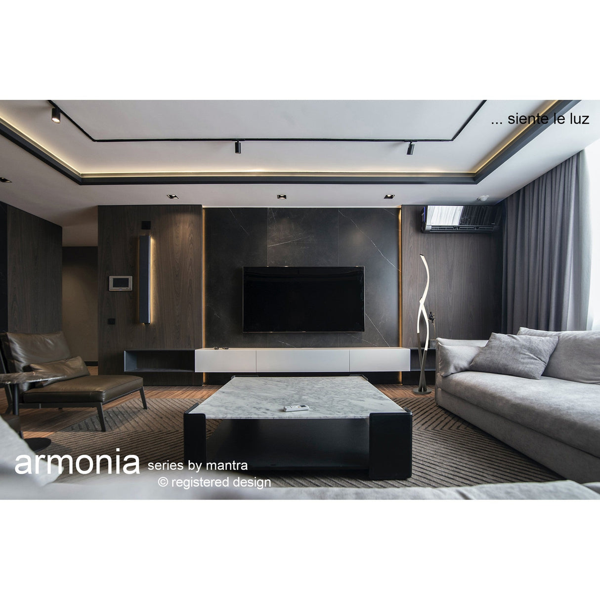 Modern living room with gray sofas, marble coffee table, flat-screen TV on a dark wall, and the Armonia LED Floor Lamp 30W 3000K - Silver & White by Mantra. Text reads: armonia series by mantra and siente la luz.