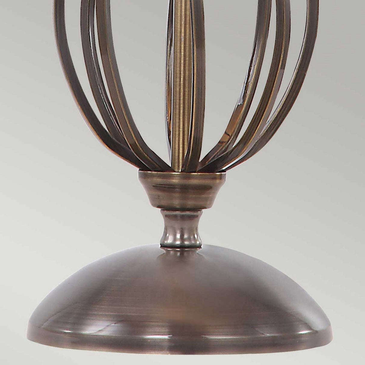 A close-up of the Artisan Table Lamp in aged brass reveals a vintage-style design with a dome-shaped base and vertical metal rods extending upward, forming an open, cage-like structure. The elegant finish of the metal wonderfully complements its artisan craftsmanship, reflecting a timeless aesthetic.