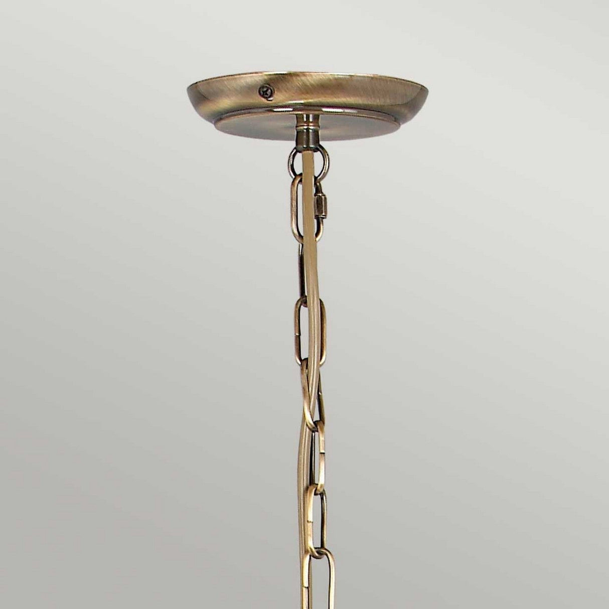Close-up of a flush convert option on the Artisan 3 Light Chandelier in aged brass, featuring a chain hanging down, perfect for suspending light fixtures. The metal has a brushed finish that pairs beautifully with the plain light gray background, making it an ideal choice for those considering an aged brass chandelier design.