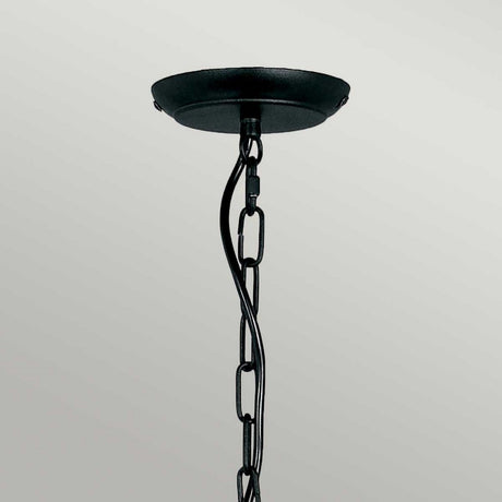A twisted metal chain and black ceiling canopy suspend the Artisan 5 Light Chandelier - Black, showcasing hand-formed scrolls against a light gray background.