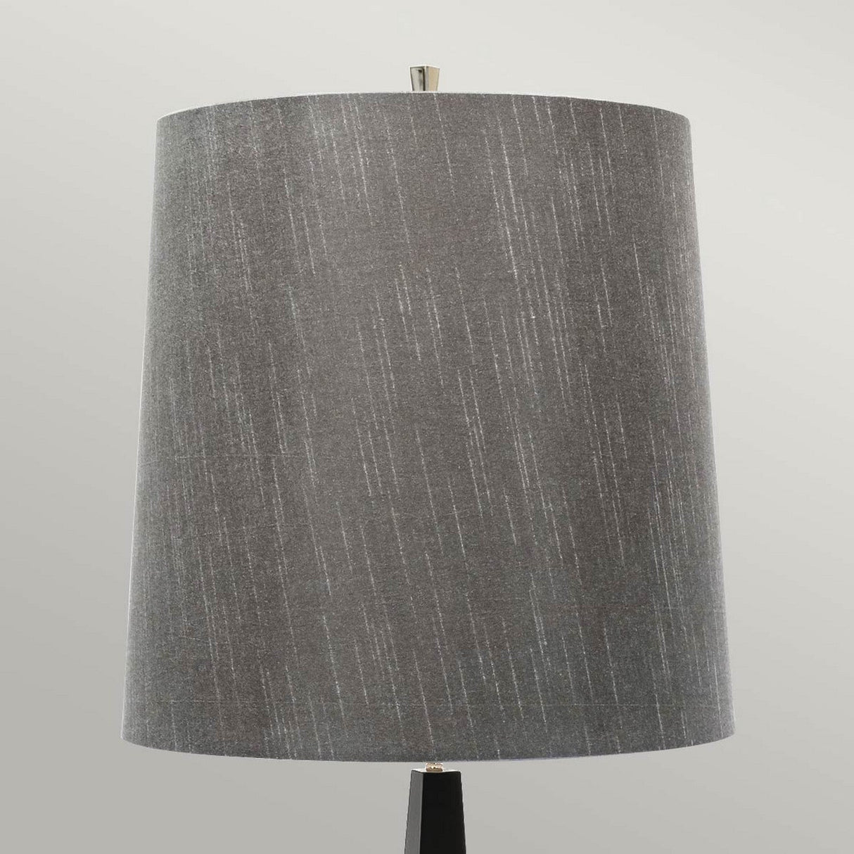 Introducing the Ascent Floor Lamp With Dark Grey Shade - Black: This contemporary floor lamp is adorned with a cylindrical, textured dark grey shade and stands against a light-colored backdrop. Its minimalist design showcases a stylish black base and top finial, capturing a sophisticated modern look.