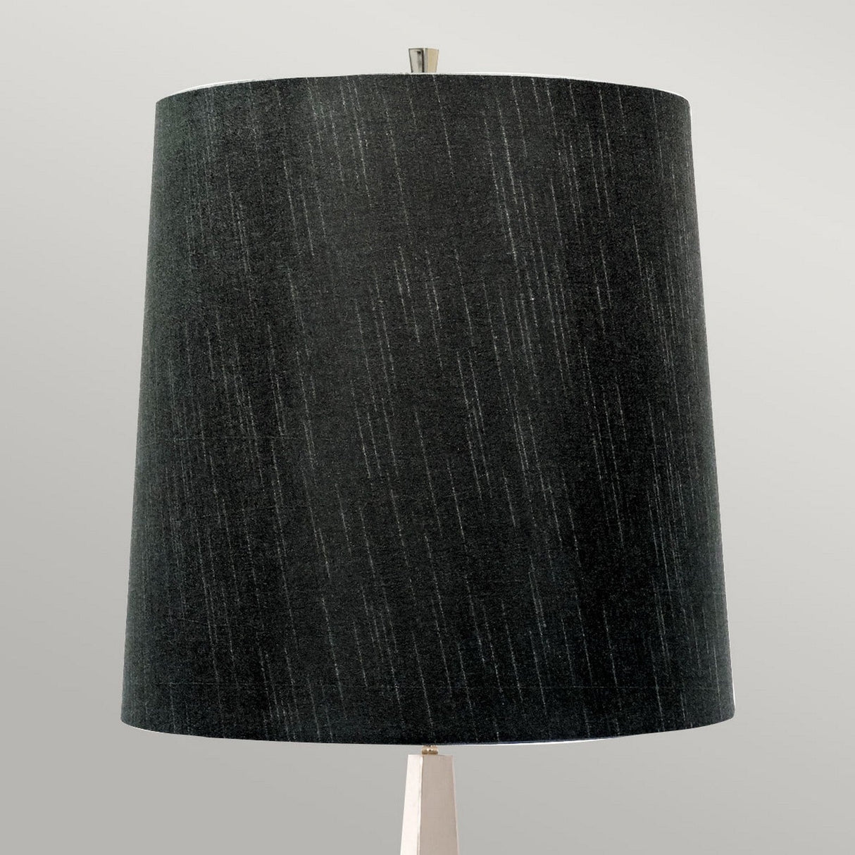 The Ascent Floor Lamp With Black Shade - Polished Nickel showcases a tall, cylindrical black shade adorned with subtle vertical white streaks. It is elegantly mounted on a thin base finished in polished nickel, all set against a light gray background to highlight its modern and minimalist design.