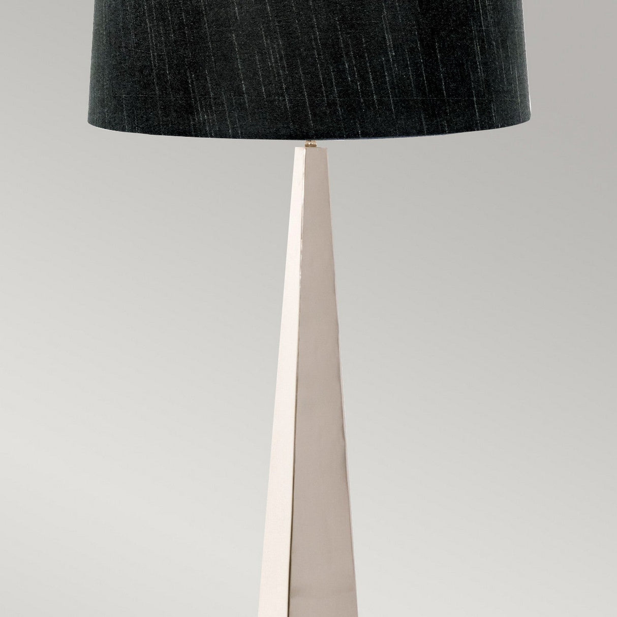 The Ascent Floor Lamp With Black Shade - Polished Nickel boasts a tall, angular base in a polished nickel finish, paired with a dark, textured black shade. Set against a plain, light gray background, it highlights a sleek and modern design that focuses on clean lines and simplicity.