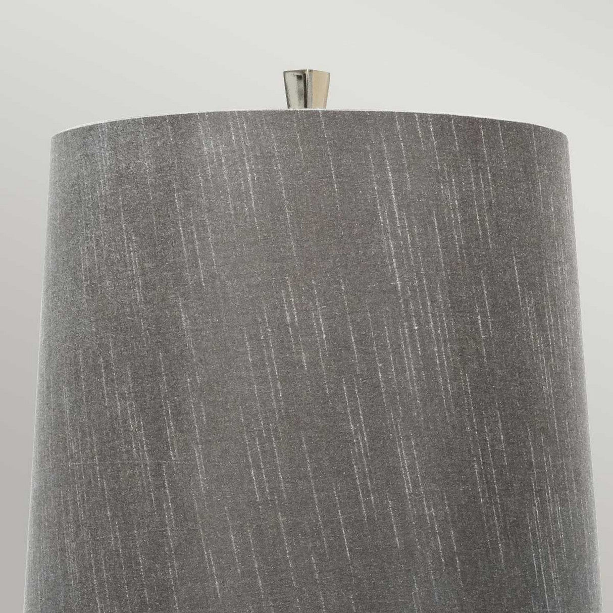 Close-up of a textured gray lampshade with a cylindrical shape and a small metallic finial on top, ideal for contemporary spaces. The minimalist design perfectly complements the Ascent Table Lamp - Black, set against a soft, neutral background.