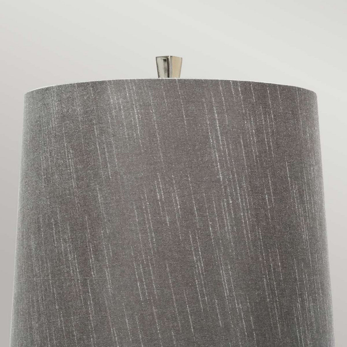 The Ascent Table Lamp With Dark Grey Shade - Polished Nickel boasts a cylindrical shade with a textured vertical line pattern, elegantly accented by a small metallic finial in polished nickel, creating an exquisite display against a light gray background.