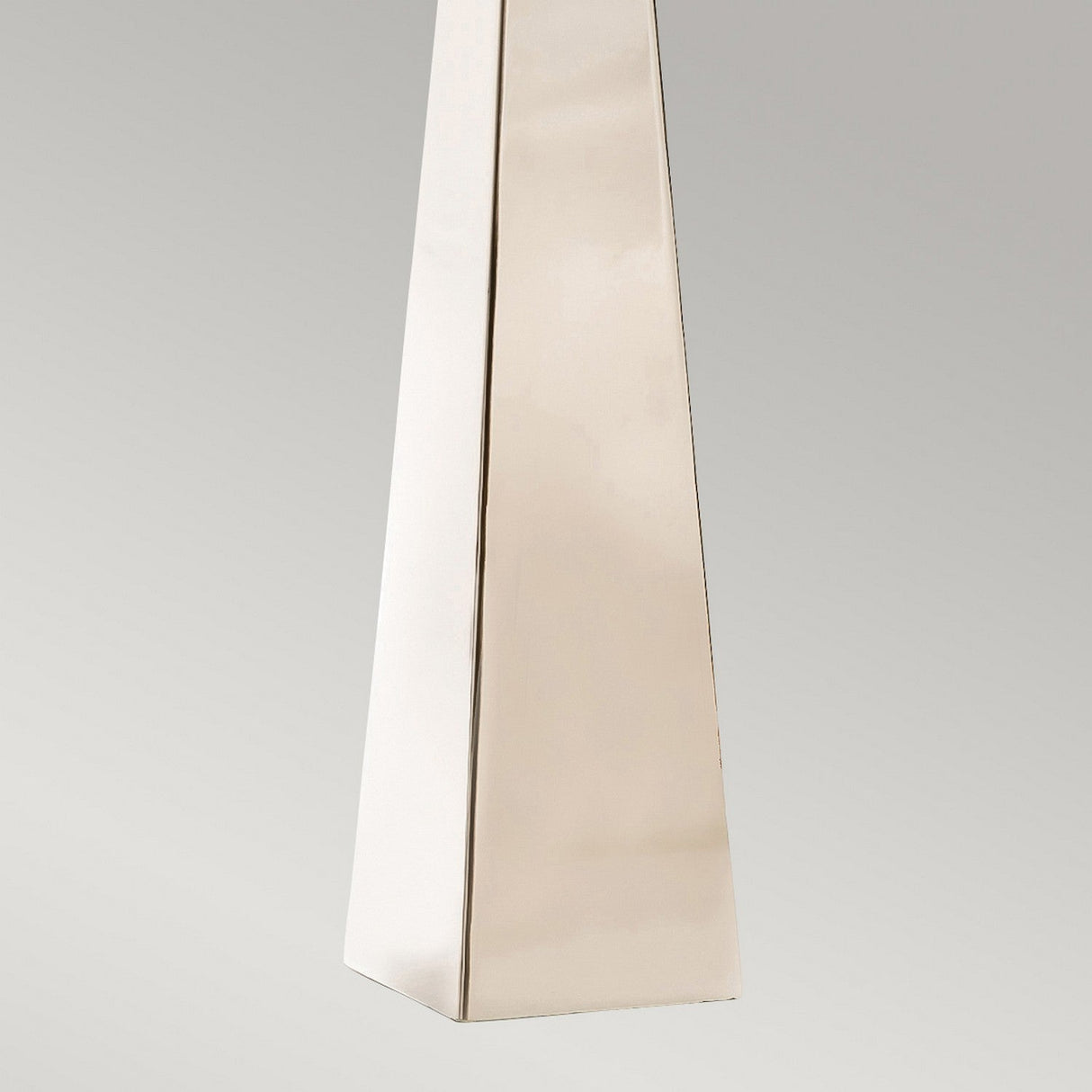 A tall, sleek Ascent Table Lamp with a polished nickel finish stands majestically against a neutral gray background, its surface smooth and reflective.