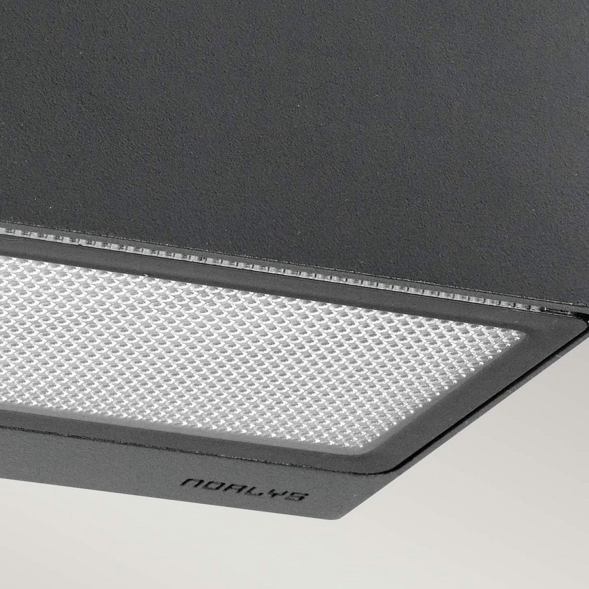A close-up of a contemporary, square-shaped ceiling light fixture features a textured, frosted glass surface framed smoothly in gray. The word NORDLUX appears on the fixture, signifying its durable IP65 rating ideal for both indoor and outdoor lighting aesthetics.