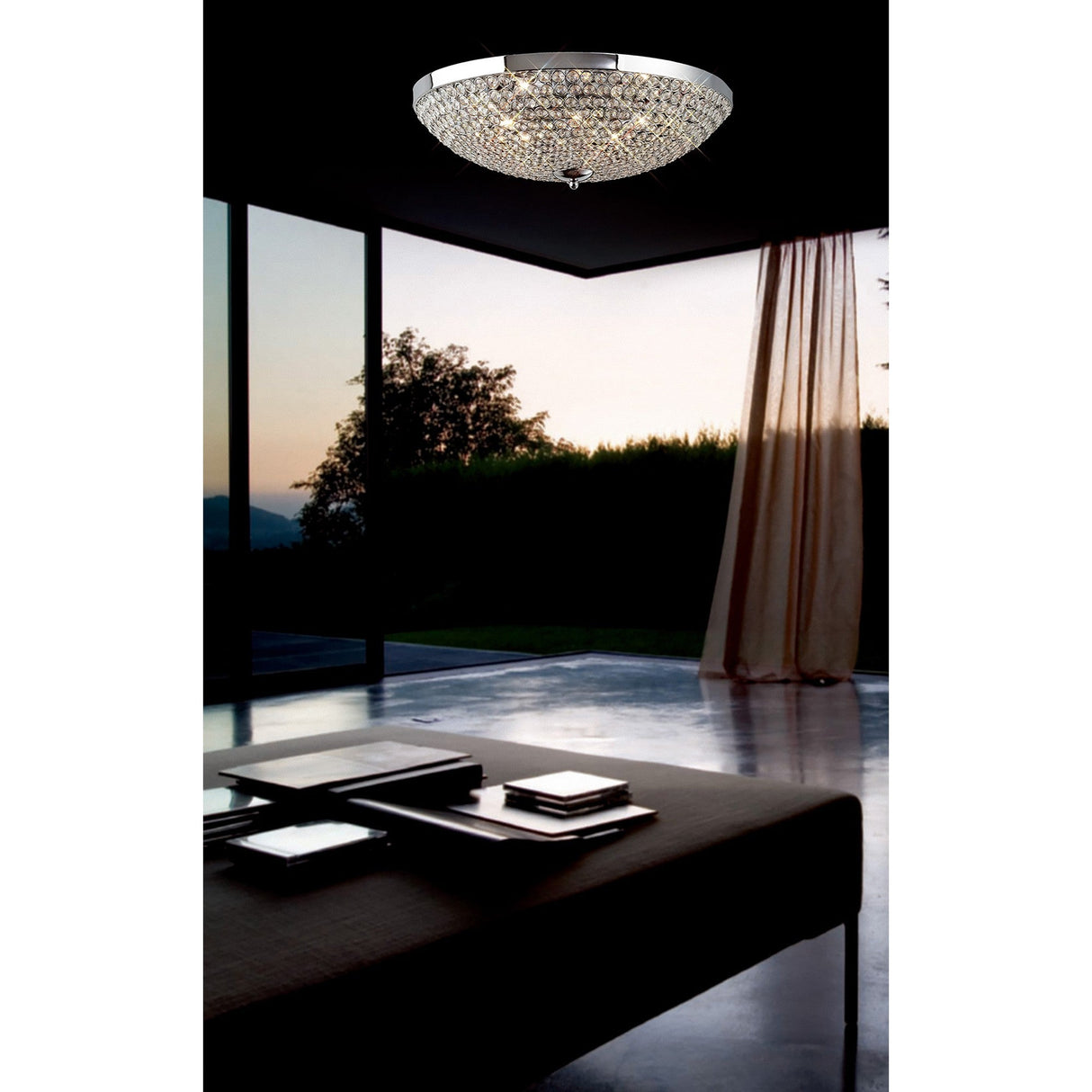Diyas Ava 9 light crystal flush ceiling light in polished chrome, mounted on a dark ceiling above a modern living space with floor-to-ceiling windows.