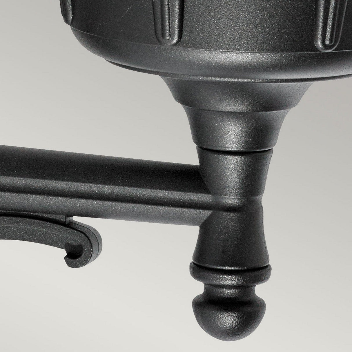 Close-up of the Bologna Outdoor 1 Light Up Wall Light in black, featuring cylindrical and pointed components connected by a horizontal rod. The fixture's surface has a smooth, matte finish. With its IP54 rating, it's ideal for a variety of environments. The backdrop is a neutral gray.